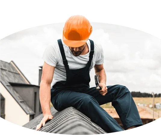 Ein Mann in einer Schutzhelm auf dem Dach sitzend.