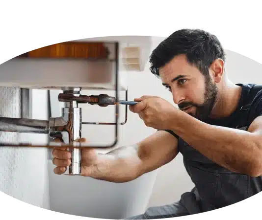 Ein Handwerker repariert ein Waschbecken in einem Badezimmer.