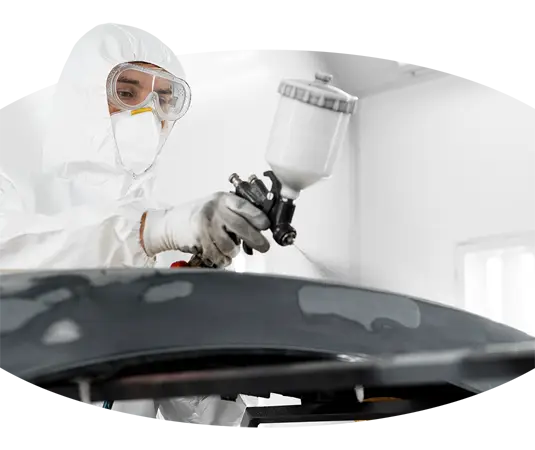 Ein Carrosserielackierer bringt Schutzlack auf ein Auto auf.