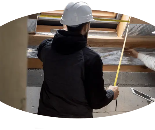 Zwei Bauarbeiter messen in ihren Kranführer-Jobs die Höhe einer Decke.